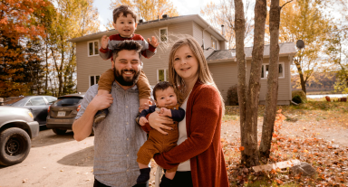 Family of four standing in front of their home